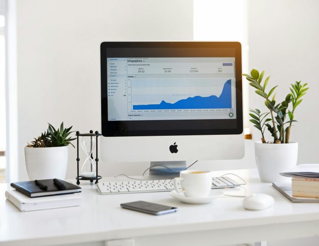 A clean, contemporary workspace featuring a desktop with analytics on the screen and plants for a fresh look.